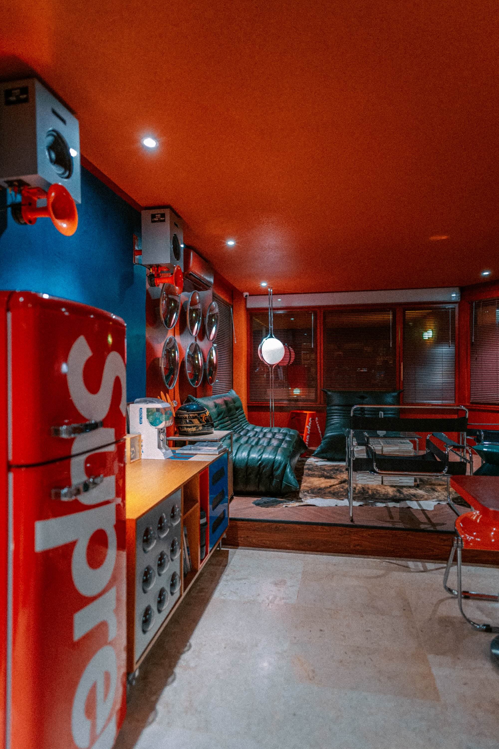 Sudut lobby dengan kulkas merah dan sofa kulit