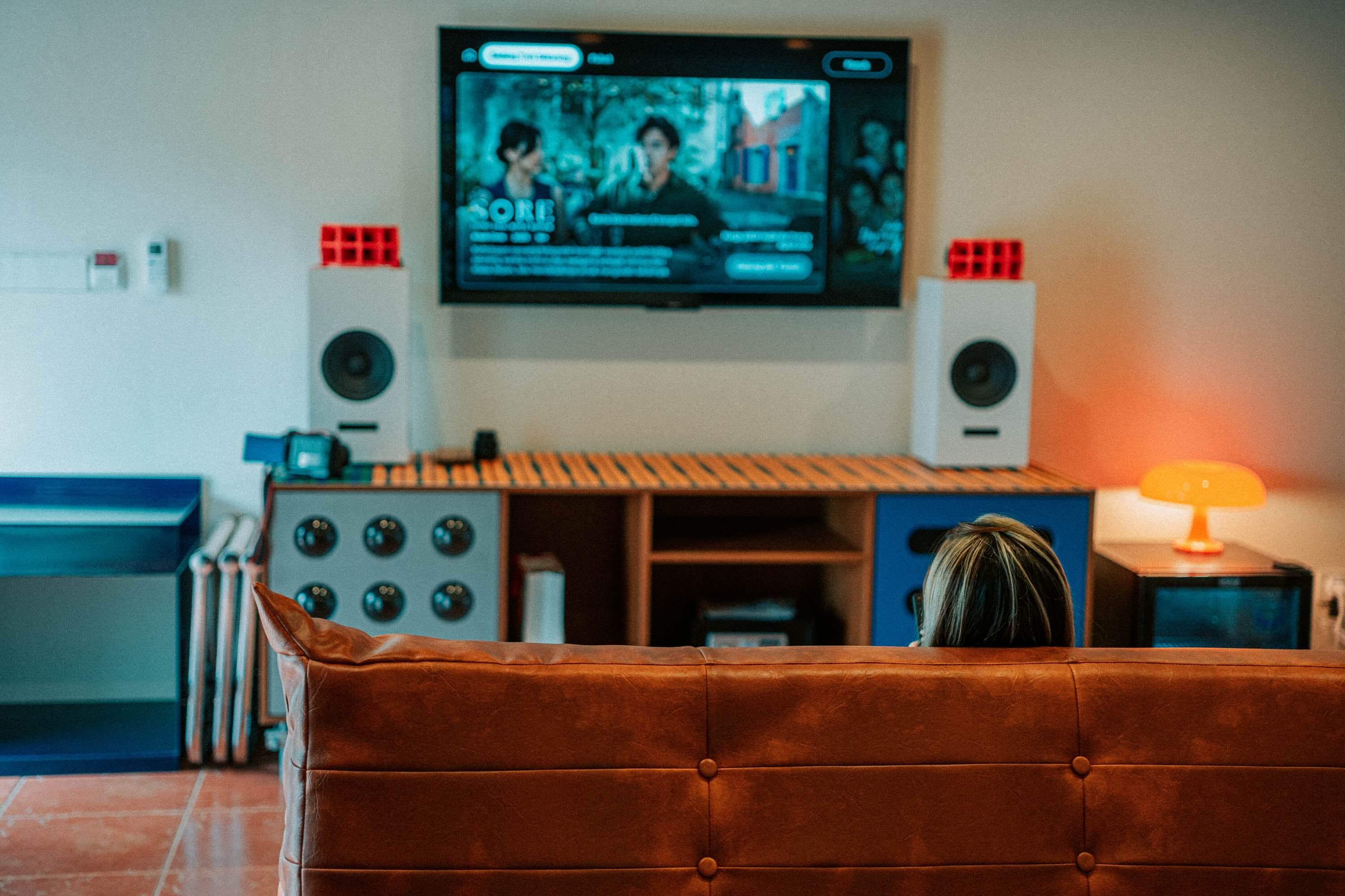 A guest watching TV from a leather sofa in the room