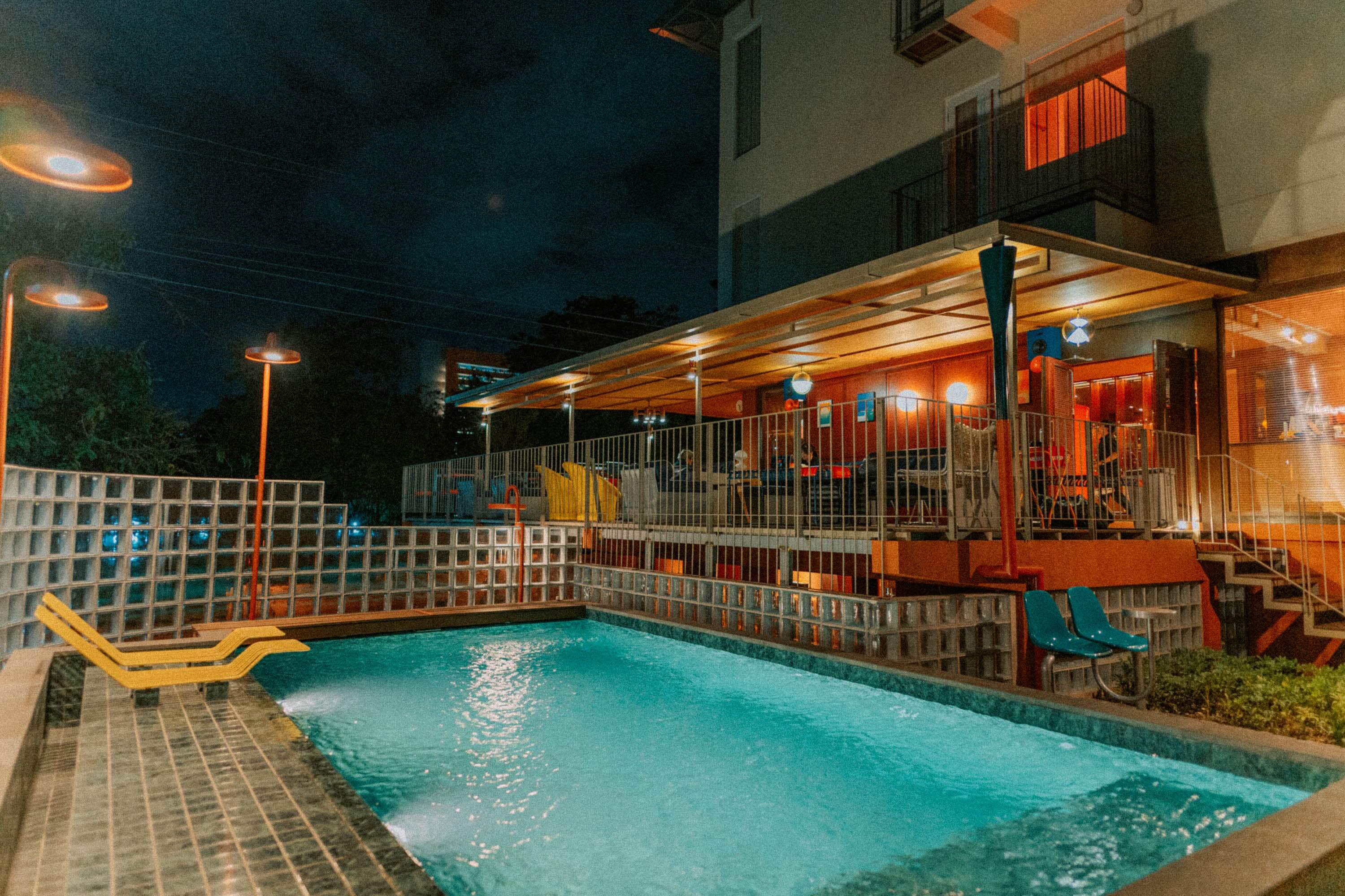 Kolam renang outdoor Aksara Hotel di malam hari dengan lampu taman