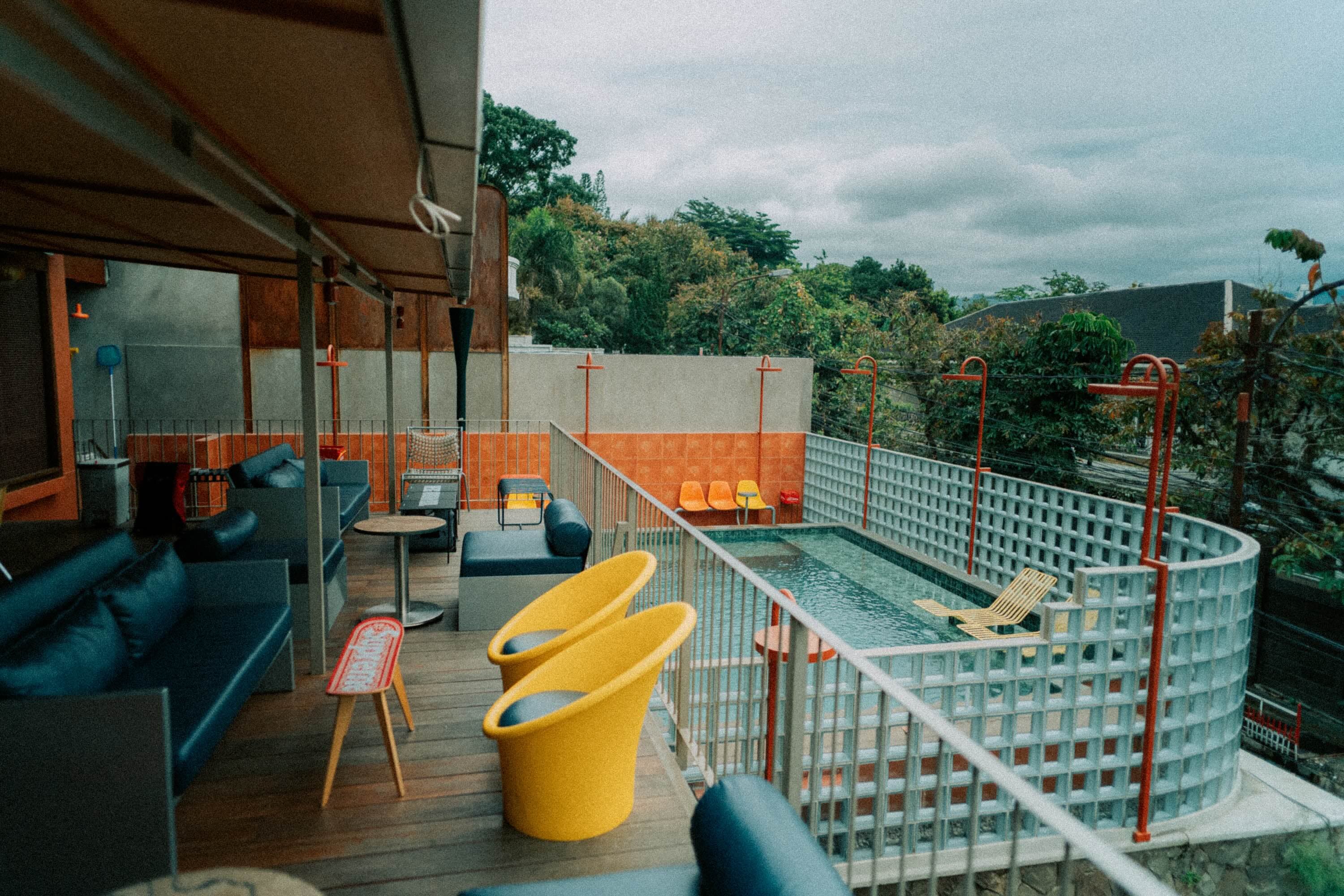 Teras Artisan Coffee dengan kursi kuning menghadap kolam renang